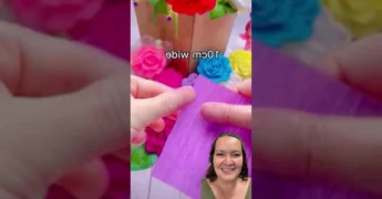 Imagem de uma mão criando uma flor roxa de papel crepom com a técnica de dobrar e torcer. Créditos: @kidica10_ no Instagram