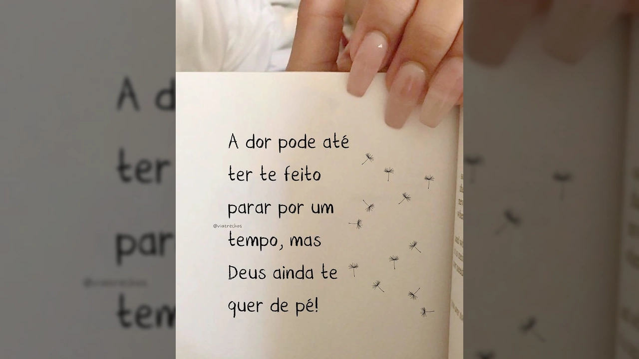 Uma folha de livro com a frase 'A dor pode até ter te feito parar por um tempo, mas Deus ainda te quer de pé!' e sementes de dente-de-leão, do Instagram @viatrechos