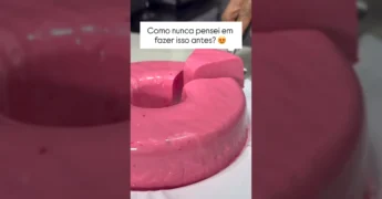 Uma sobremesa rosa vibrante de gelatina e leite condensado cortada em pedaços, com uma calda de chocolate por cima. Créditos para @receiitasdiarias no Instagram.