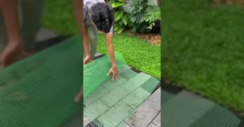 Foto de um homem criando uma torre de orquídeas vertical usando tela verde e substrato, com diversas orquídeas coloridas já plantadas / Instagram @tocos_e_cia
